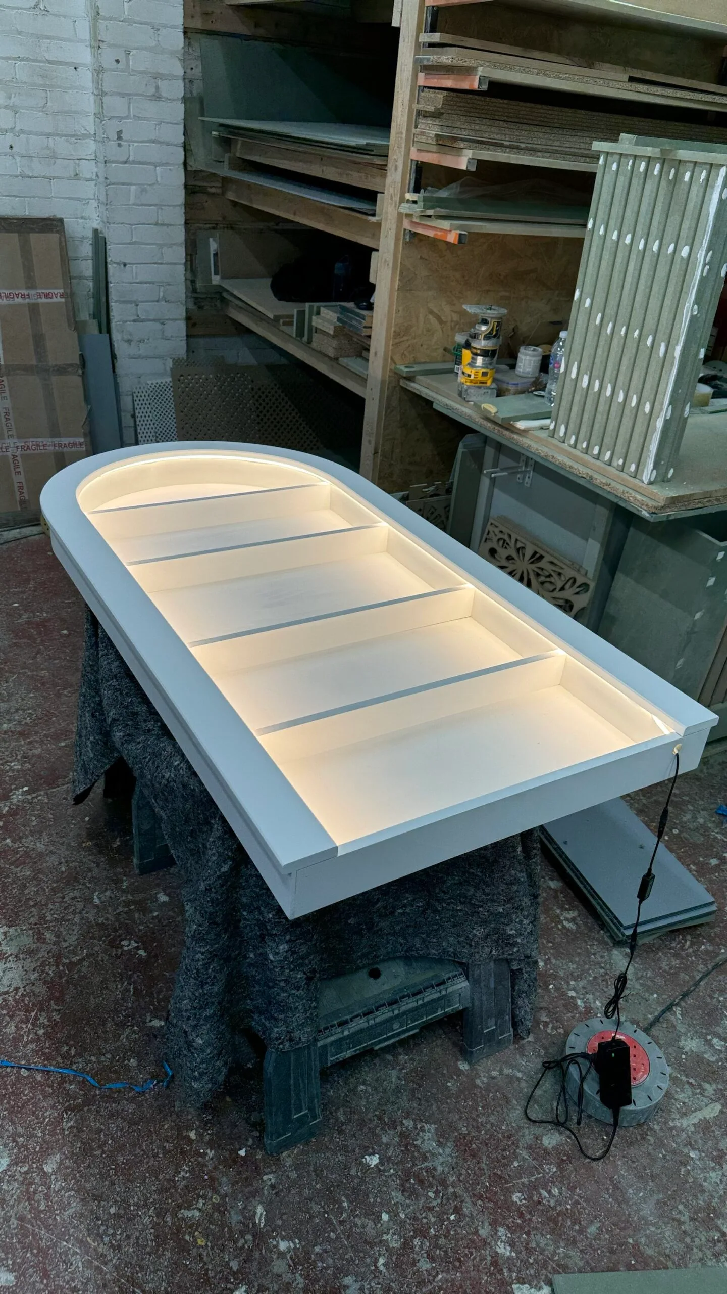 Bespoke curved floating salon wall unit with warm white LED lighting and white backing