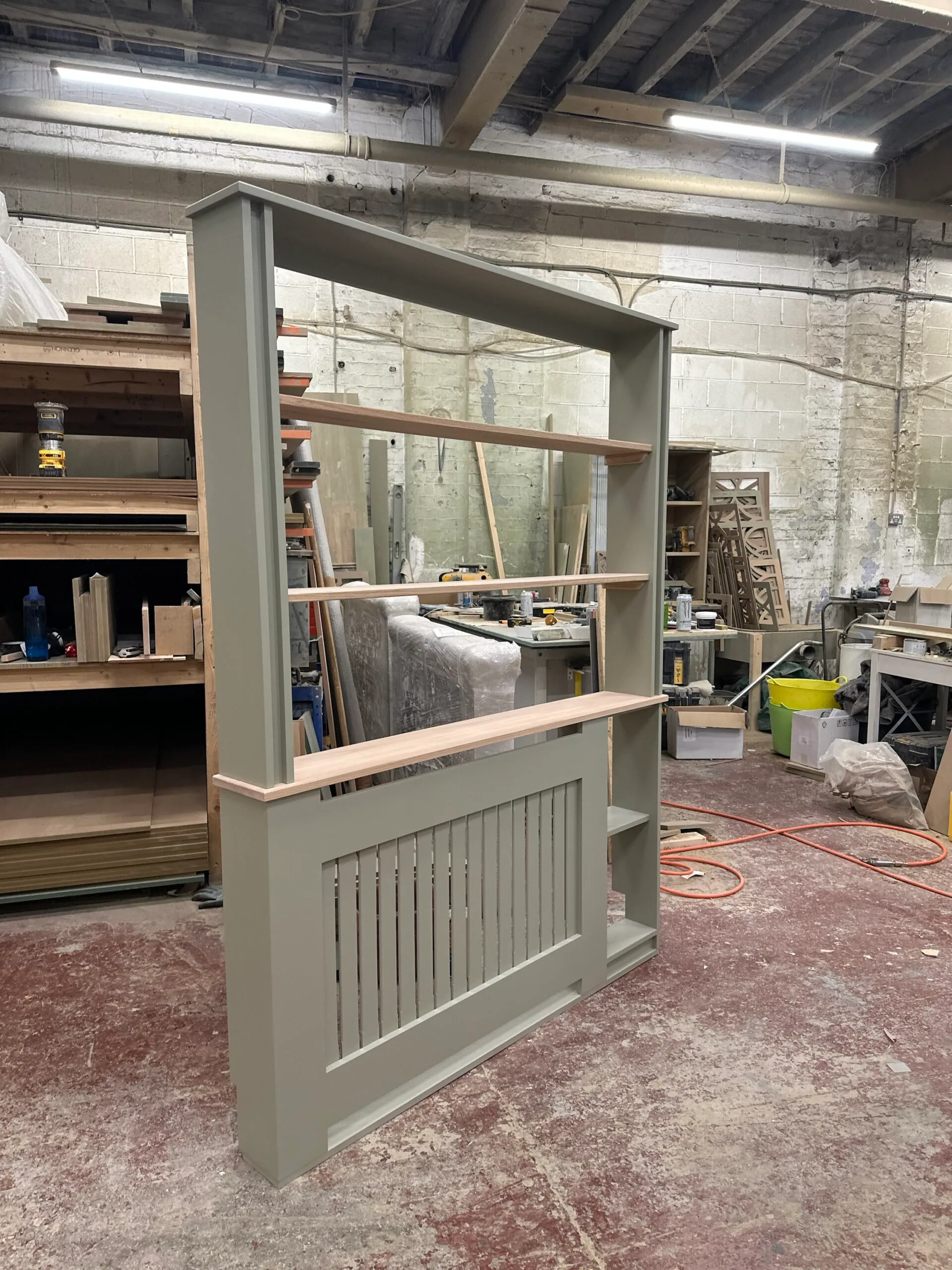 Bespoke white radiator cover with built-in side bookshelf and solid oak top in home office