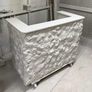 A stylish, modern reception desk or bar counter with a textured white stone-like front and a smooth white countertop