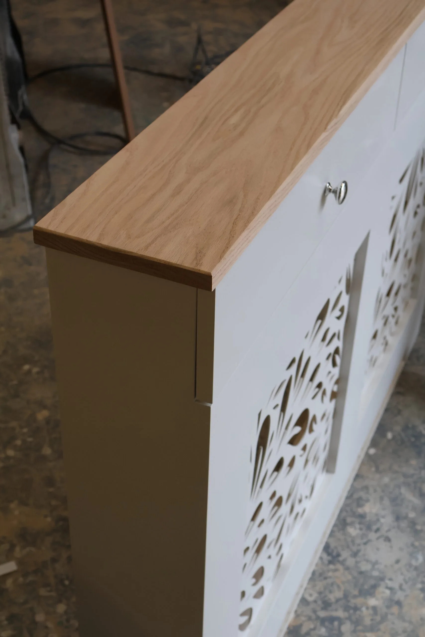 Bespoke white radiator cover with decorative floral grill pattern and natural oak top