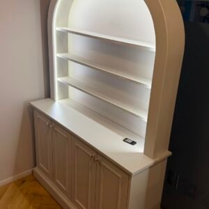 White cabinet with a curved bookcase featuring illuminated open shelving and classic panelled base storage.