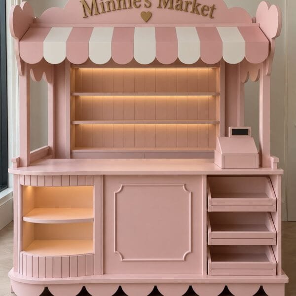 Handmade wooden Minnie's Market children's play market stall in pastel pink with integrated LED shelving and cash register
