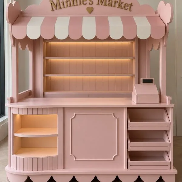 Handmade wooden Minnie's Market children's play market stall in pastel pink with integrated LED shelving and cash register